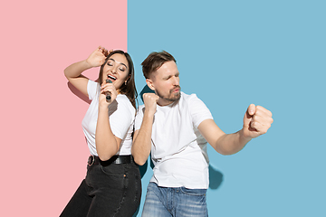 Image showing Young emotional man and woman on pink and blue background