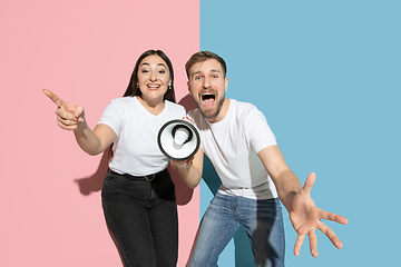 Image showing Young emotional man and woman on pink and blue background