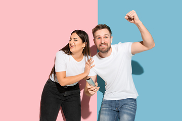 Image showing Young emotional man and woman on pink and blue background