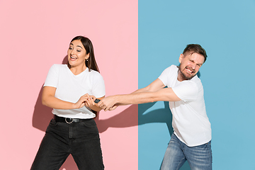 Image showing Young emotional man and woman on pink and blue background