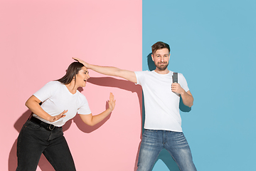 Image showing Young emotional man and woman on pink and blue background