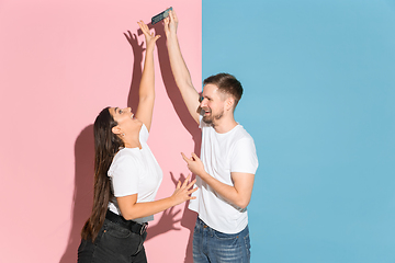 Image showing Young emotional man and woman on pink and blue background