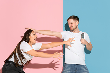 Image showing Young emotional man and woman on pink and blue background