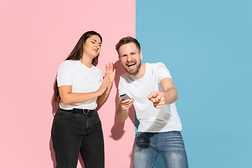 Image showing Young emotional man and woman on pink and blue background