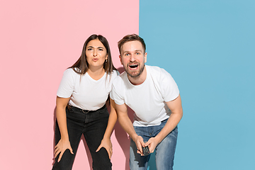 Image showing Young emotional man and woman on pink and blue background