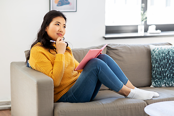 Image showing asian woman with diary sitting on sofa at home