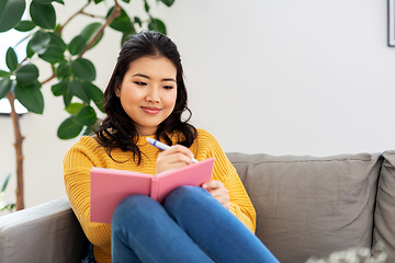 Image showing asian woman with diary sitting on sofa at home