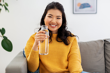 Image showing smiling asian young woman drinking water at home
