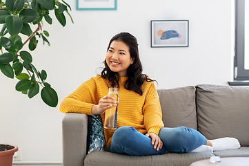 Image showing smiling asian young woman drinking water at home