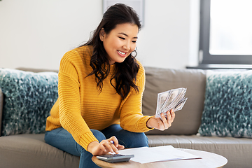 Image showing woman with money, papers and calculator at home