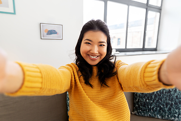 Image showing smiling asian young woman taking selfie at home