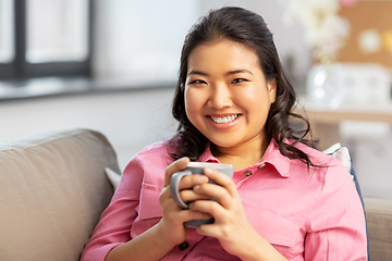 Image showing smiling asian young woman drinking coffee at home