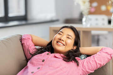 Image showing happy asian woman lying on sofa and dreaming