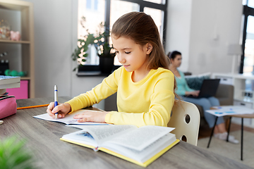 Image showing student girl with book writing to notebook at home