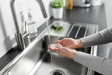 Image showing woman washing hands with liquid soap in kitchen