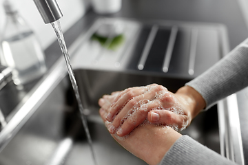 Image showing woman washing hands with liquid soap in kitchen