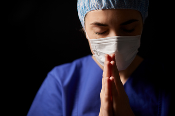 Image showing female doctor or nurse in face mask praying