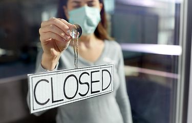 Image showing woman in mask hanging banner closed on door