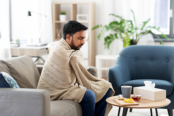 Image showing sick young man in blanket with hot tea at home