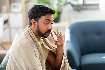 Image showing sick indian man using nasal spray at home