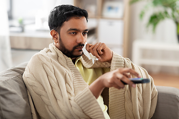 Image showing sick man with paper tissue and tv remote at home