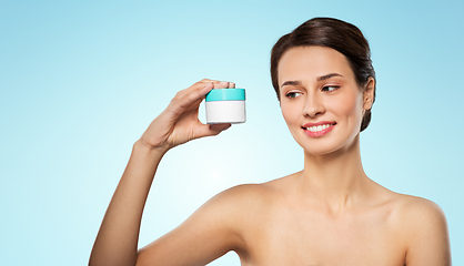 Image showing happy young woman holding jar of cream