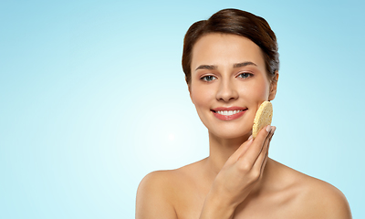 Image showing young woman cleaning face with exfoliating sponge