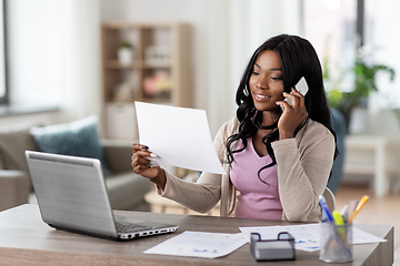 Image showing woman with papers calling on phone at home office