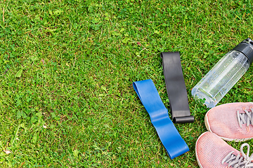 Image showing Ladie's fitness rubber bands and sneakers on the green grass background
