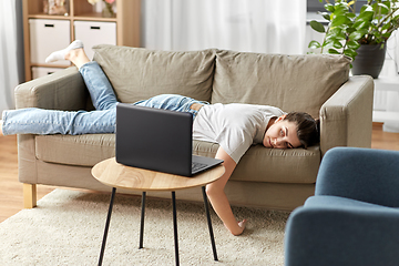 Image showing bored woman with laptop lying on sofa at home