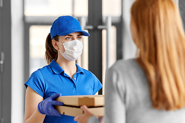 Image showing delivery girl in mask giving pizza boxes to woman