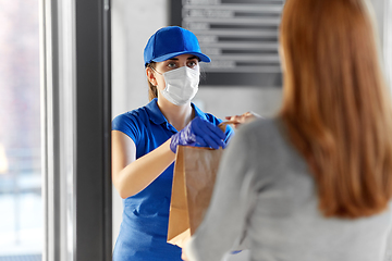 Image showing delivery girl in mask giving paper bag to woman