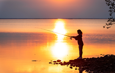 Image showing Woman fishing on Fishing rod spinning in Finland at sunset.