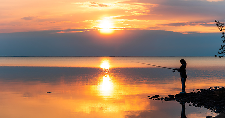 Image showing Woman fishing on Fishing rod spinning in Finland at sunset.