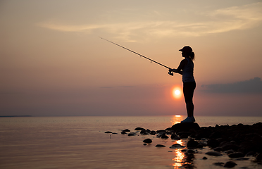 Image showing Woman fishing on Fishing rod spinning in Finland at sunset.