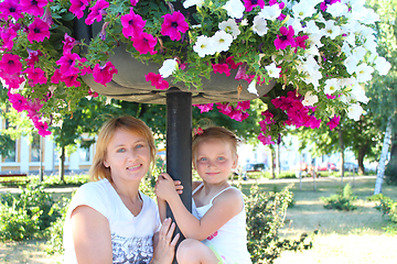 Image showing mother and her daughter and many flowers in city park