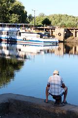 Image showing fisherman fishing in the city river near motor ship 