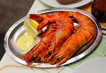 Image showing Jumbo shrimps with lemon and sauce on metal plate