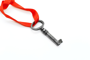 Image showing Vintage silver key with red ribbon on white background