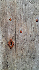 Image showing Vintage wooden door with rusty keyhole and rivets