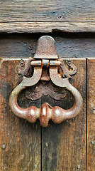 Image showing Vintage doorknocker close-up on weathered wooden door texture