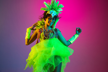 Image showing Beautiful young woman in carnival and masquerade costume on gradient studio background in neon light