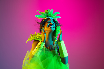 Image showing Beautiful young woman in carnival and masquerade costume on gradient studio background in neon light