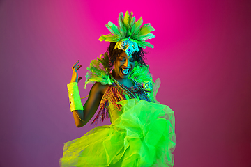 Image showing Beautiful young woman in carnival and masquerade costume on gradient studio background in neon light