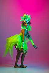 Image showing Beautiful young woman in carnival and masquerade costume on gradient studio background in neon light