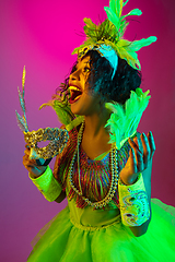 Image showing Beautiful young woman in carnival and masquerade costume on gradient studio background in neon light