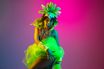 Image showing Beautiful young woman in carnival and masquerade costume on gradient studio background in neon light