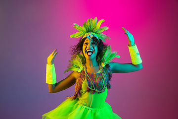 Image showing Beautiful young woman in carnival and masquerade costume on gradient studio background in neon light