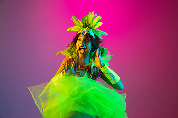 Image showing Beautiful young woman in carnival and masquerade costume on gradient studio background in neon light