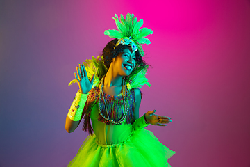 Image showing Beautiful young woman in carnival and masquerade costume on gradient studio background in neon light